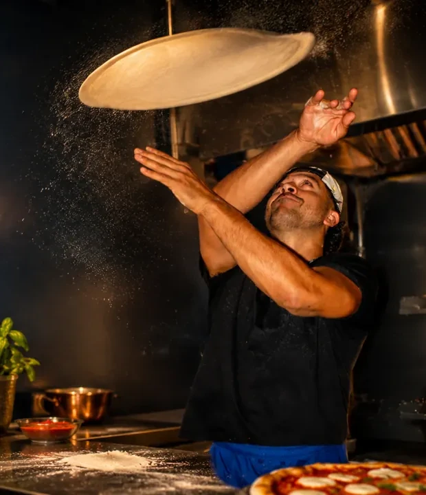 Pizzaiolo tossing fresh dough in the Diamond Pizza kitchen late at night